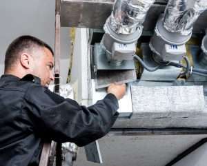 Homeowner replacing furnace air filter to improve airflow and reduce energy costs in Surrey residence