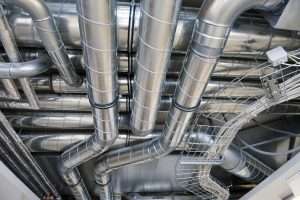Commercial HVAC system maintenance showing technician inspecting ducts and coils in Lower Mainland building