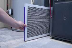 Technician replacing furnace filter during duct cleaning service in Surrey