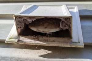 Lint-clogged exterior dryer vent hood on a Surrey home showing fire hazard buildup
